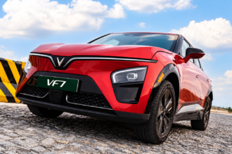 Red VinFast VF 7 electric SUV illustrating fuel savings from EV ownership.